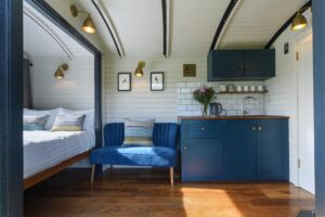 Bed, chair and kitchenette inside the Merlin Shepherds Hut