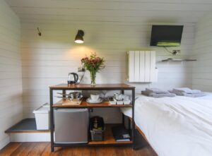 Bed, kitchen amenities and decor in the Pheasant Shepherds Hut